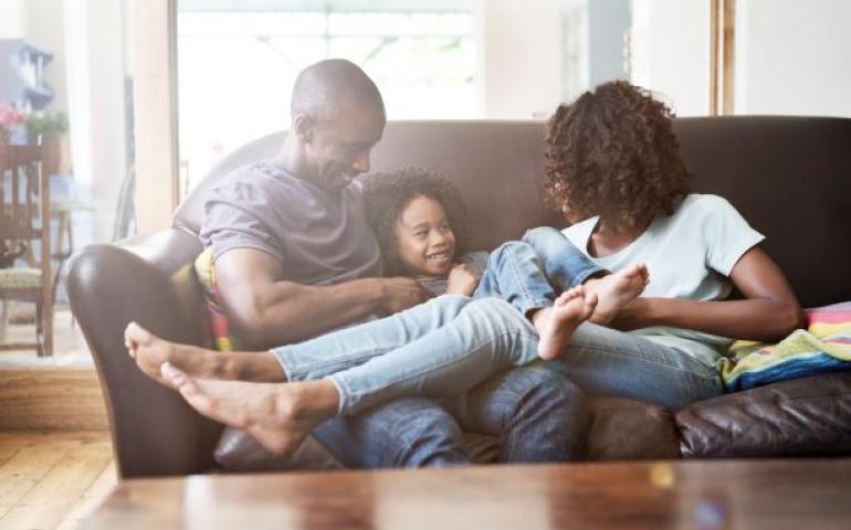 family of 3 on couch laughing 