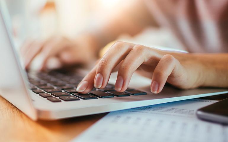 Female hands typing on a laptop computer.