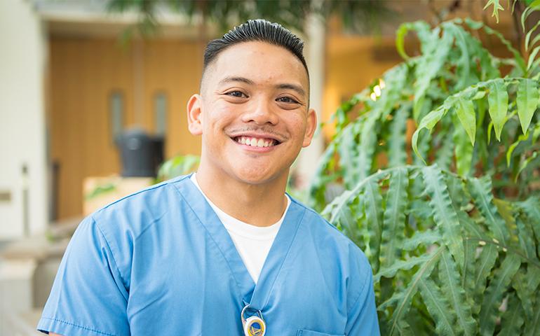 Male vocational nurse standing inside corridor of Laguna Honda Hospital in San Francisco.