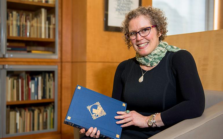 Photo Curator seated with a large old book open in the San Francisco Historical Photograph Collection at the San Francisco History Center in the San Francisco Main Branch of the Public Library.