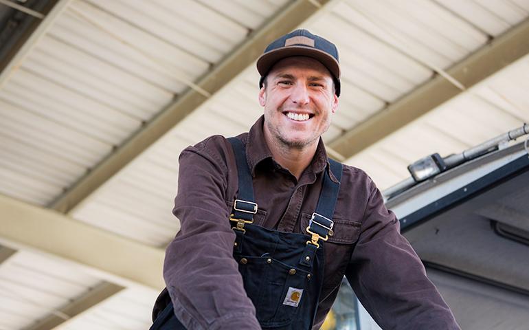 Smiling diver working for the Port of San Francisco inside Pier 50 holding staircase rail in front of him.