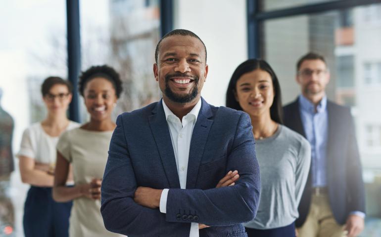 man in suit standing with employees