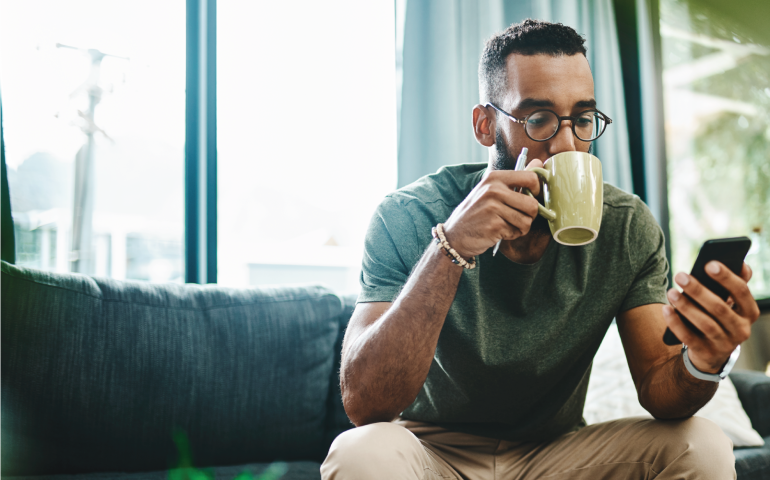 man sitting drinking coffee looking at phone
