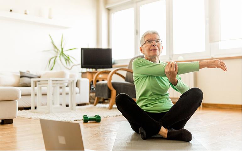 Senior woman stretching to virtual classes