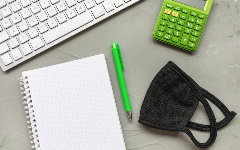 Desk with notepad, computer, mask
