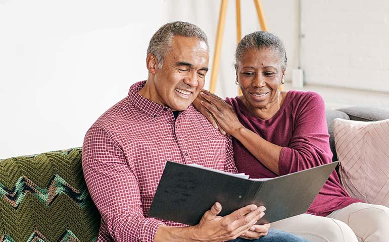 Retiree couple sitting on couch looking at notebook