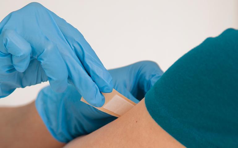 Image of a person getting a bandaid from a nurse.