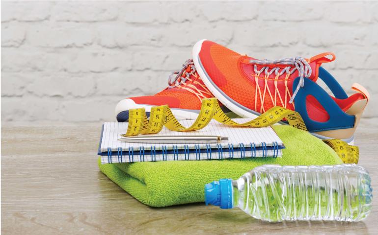 Running shoes stacked on notebook with water and towel 