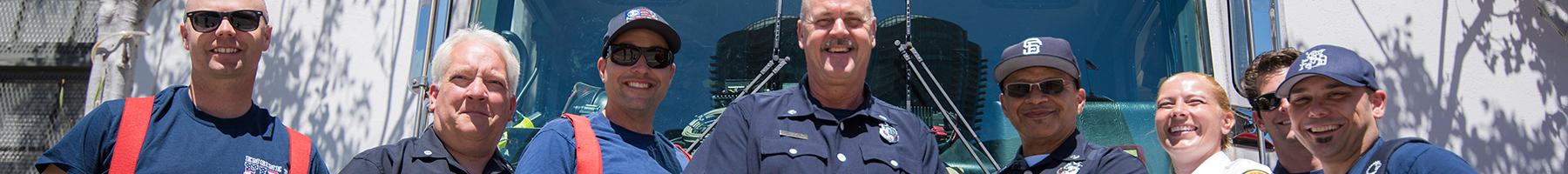 Image of a group of City and County of San Francisco firefighters posing together in front of a fire truck along the Embarcadero in San Francisco.