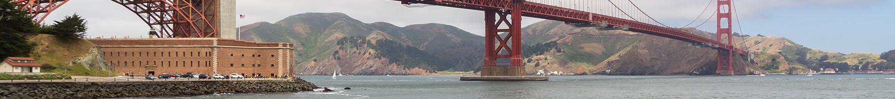 View of Fort Point underneath Golden Gate Bridge with big and strong iron chain link fence along the SF Bay