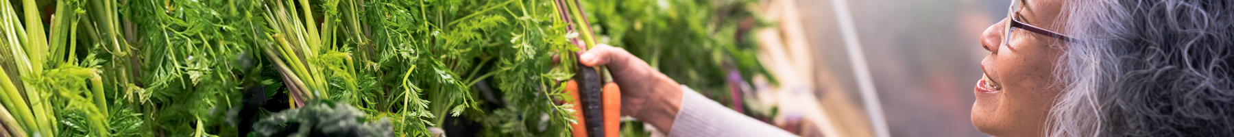 Retiree lady holding carrots at a supermarket